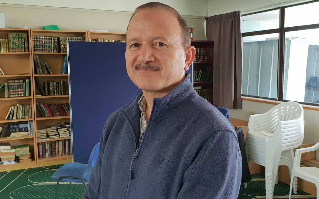 Man stands in front of bookcase and chairs