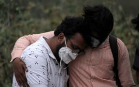 A man is consoled by his relative during the burial of his father, who died of coronavirus (Covid-19), at a graveyard in New Delhi on April 16, 2021.