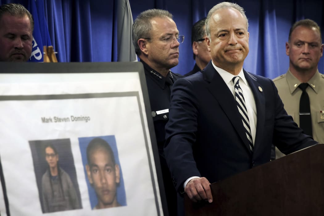 US Attorney Nick Hanna stands next to photos of Mark Steven Domingo during a news conference.