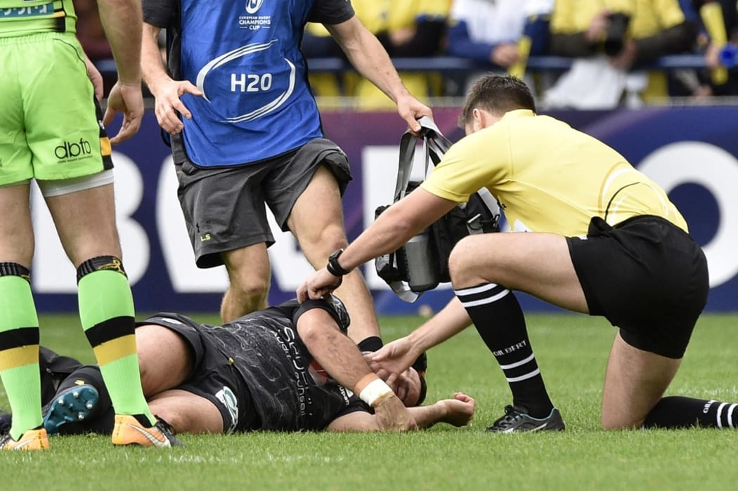 The referee (R) tends to Clermont's French scrum-half Morgan Parra (Bottom) suffering from concussion during the European Rugby Champions Cup match ASM Clermont Auvergne vs Northampton Saints at the Marcel-Michelin stadium in Clermont-Ferrand