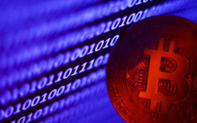 A binary code displayed on a laptop screen and representation of Bitcoin are seen in this illustration photo taken in Krakow, Poland on November 2, 2023.