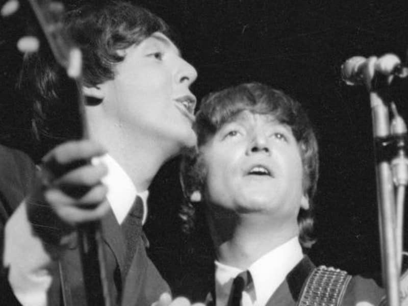 Paul McCartney and John Lennon singing together.