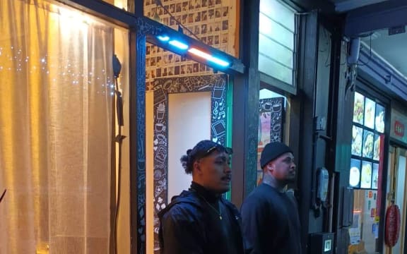 An image of two bouncers standing outside a venue.
