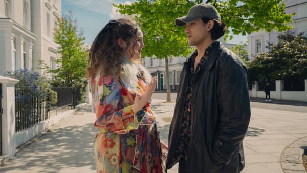 Meg Stalter standing face to face outdoors with Will Sharpe in the Netflix series Too Much.