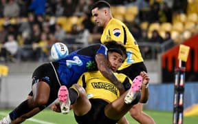 Siale Lauaki of the Hurricanes is tackled by Rieko Ioane.