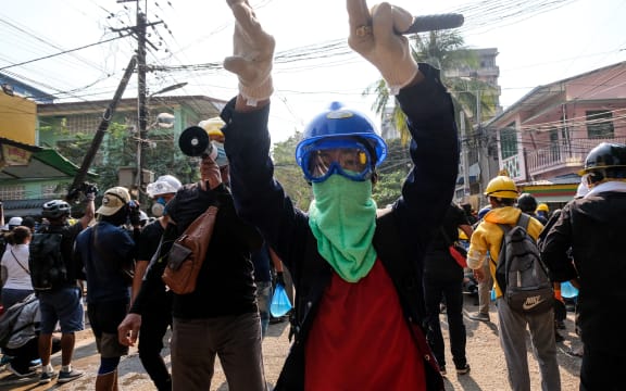 A protester gestures hand to move aside on path for protesters to run  during the riot force crackdown during an anti-coup protest in Yangon, yesterday.