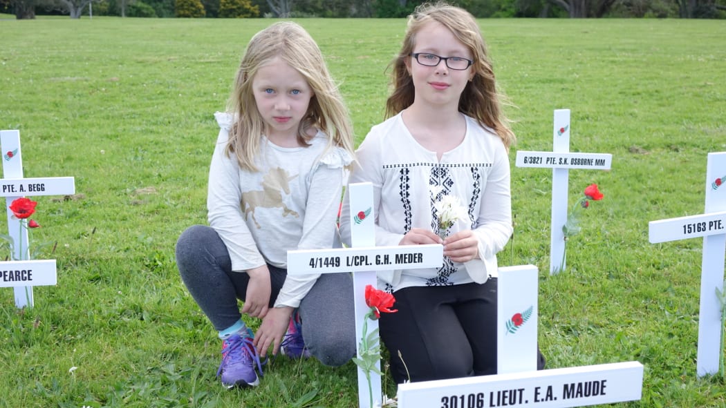 Rose Meder, 6, and sister Ruby, 10, at a cross commemorating their great great uncle.