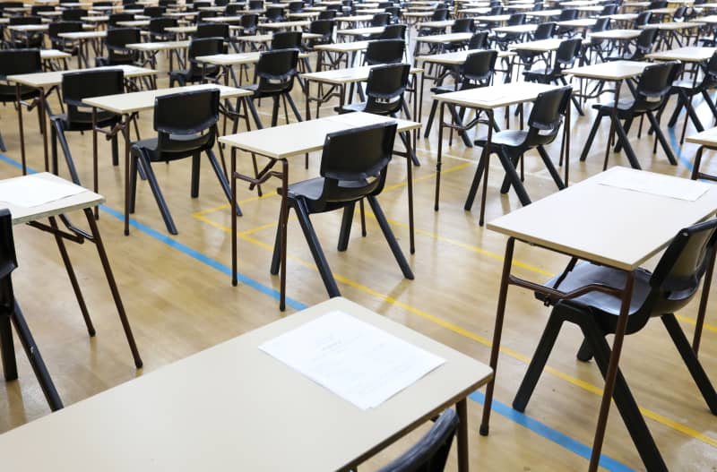 View of large exam room hall and examination desks tables lined up in rows ready for students at a high school to come and sit their exams tests papers.