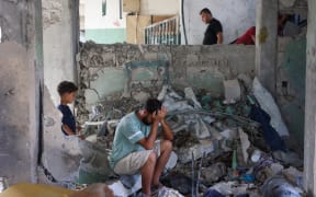 A man reacts as he sits amid the rubble at the Fahmi Al-Jarjawi School in Gaza City on 26 May, 2025, following an Israeli strike.