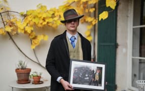 Pedro Elias Garzon Delvaux poses with an Associated Press photo of him outside the Louvre on the day of the crown jewels heist on November 8 in Rambouillet, south of Paris.