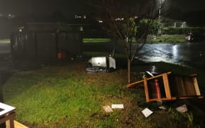 Debris strewn across the ground, including a barbeque and lawn chairs.