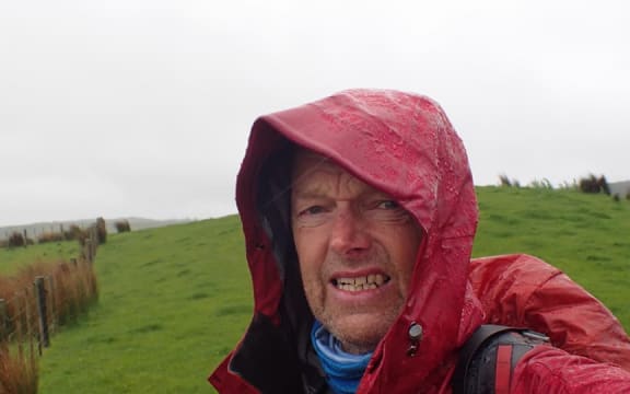 A head and shoulders shot of Bruce Hopkins huddling in his rain jacket.