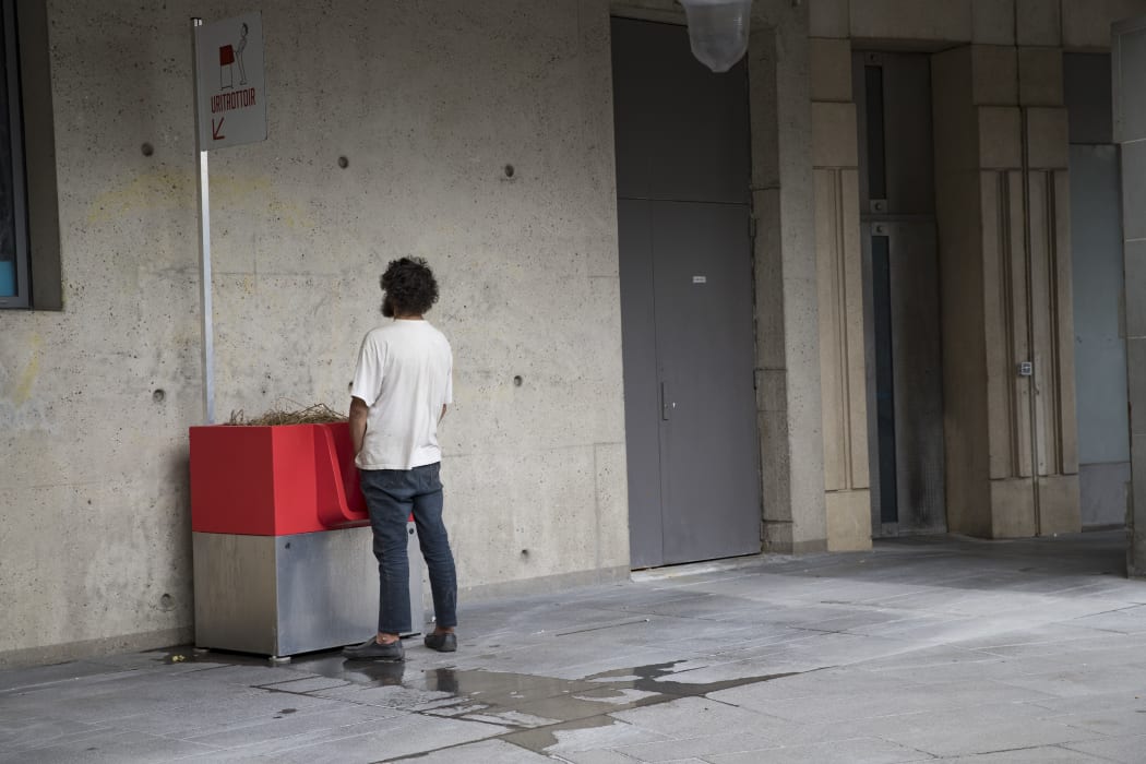 A man uses a "uritrottoir" public urinal on August 13, 2018, near the Gare de Lyon in Paris.