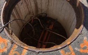 An open manhole with cables inside.