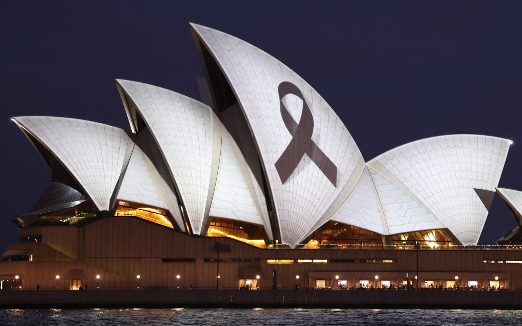 A black ribbon is projected onto the Sydney Opera House on April 15, 2024, as a mark of respect for the victims of the Westfield Bondi Junction shopping mall attack. A 40-year-old knifeman with mental illness roamed the packed shopping centre on April 13, killing six people and seriously wounding a dozen others. (Photo by DAVID GRAY / AFP)