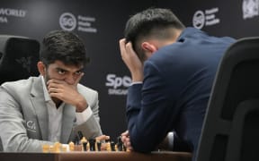 Dommaraju Gukesh, left, looks reacts while playing against Ding Liren during the world chess championship.