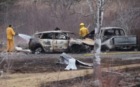 A Wentworth volunteer firefighter douses hotspots near destroyed vehicles linked to Sunday's deadly shooting rampage on April 20, 2020 in Wentworth Centre, Nova Scotia, Canada.