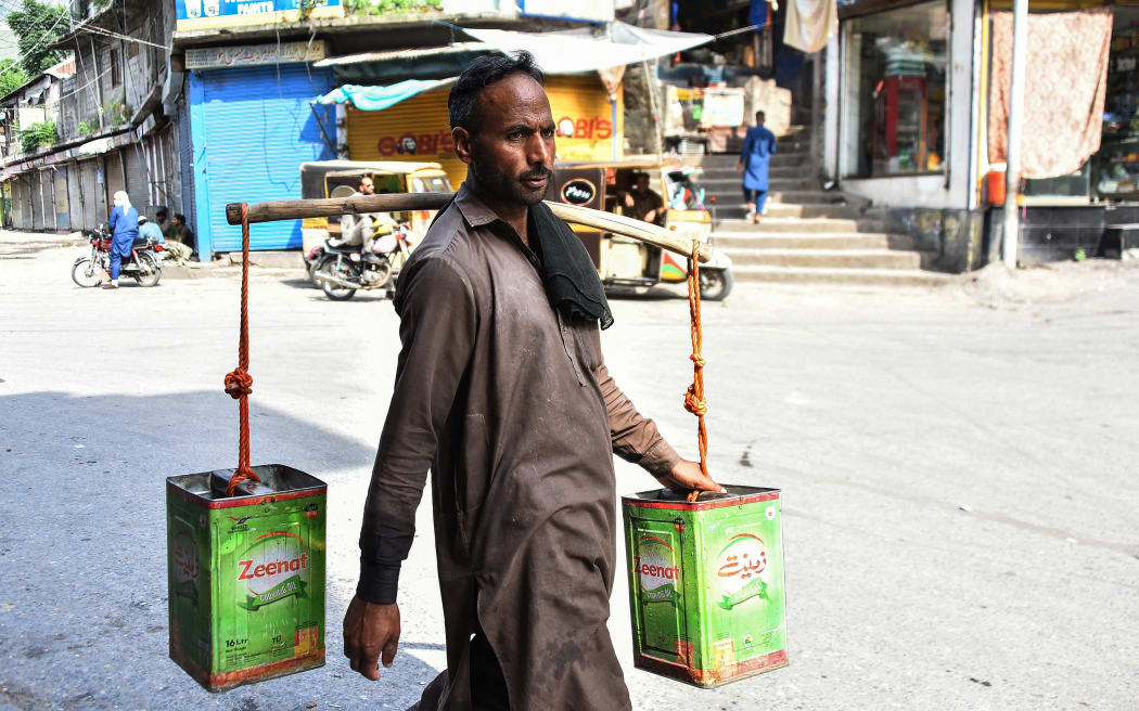 A man carries water containers as he walks along a street in Muzaffarabad, the capital of Pakistan-administered Kashmir.