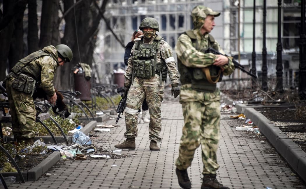 Russian soldiers walks along a street in Mariupol as Russian troops intensify a campaign to take the strategic port city.