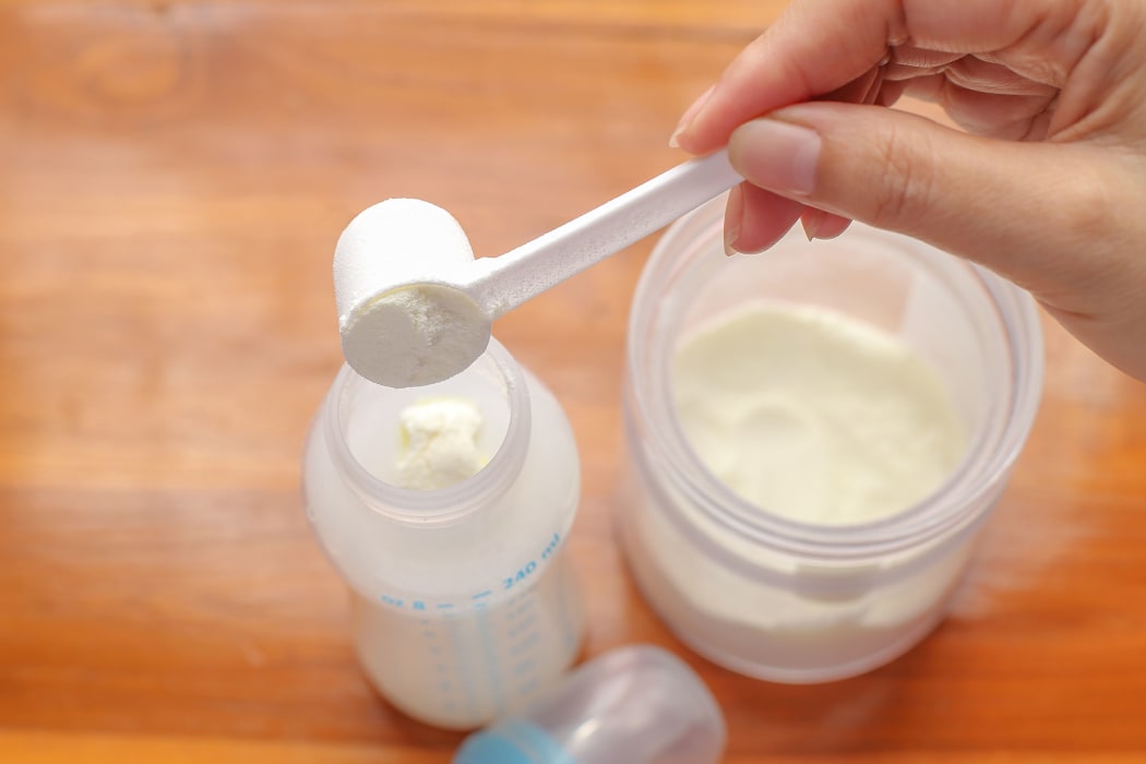 putting powdered milk into a baby bottle