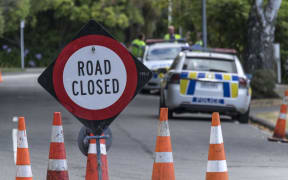 Road closed sign with two police cars in the background on Worsley Road in Christchurch during the Christchurch fires. 16 February 2017