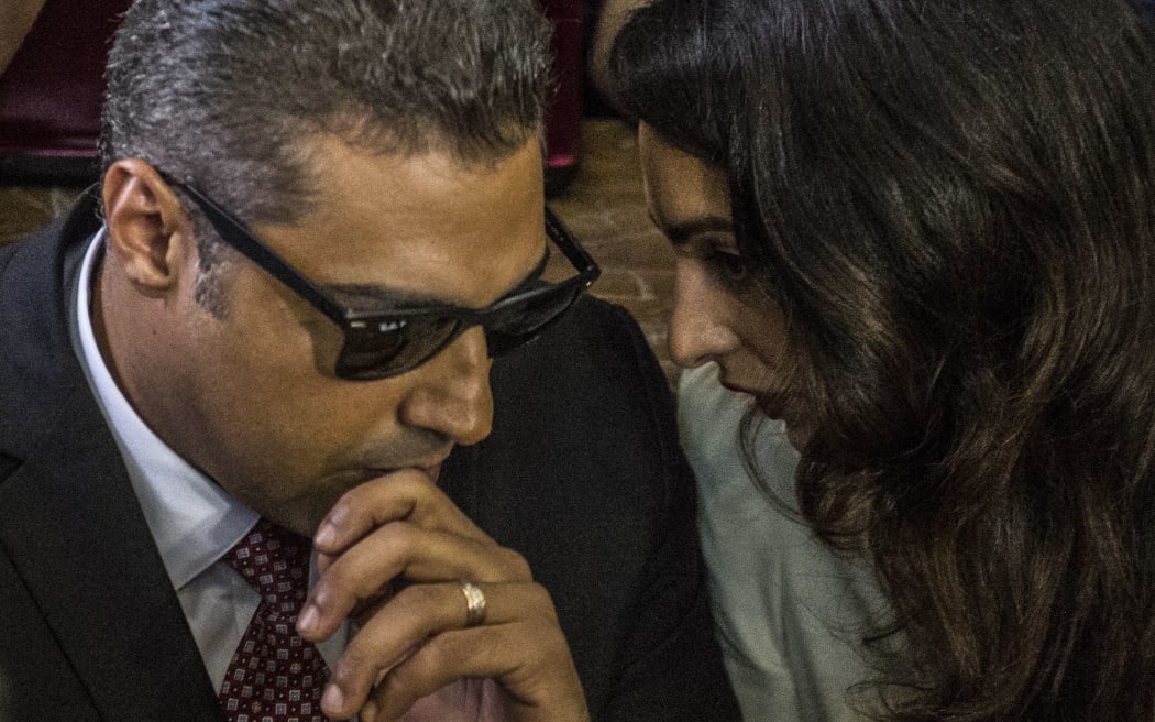 Al-Jazeera journalist, Canadian Mohamed Fahmy (L), talks to human rights lawyer, Amal Clooney (R), during the retrial in the capital Cairo on August 29, 2015