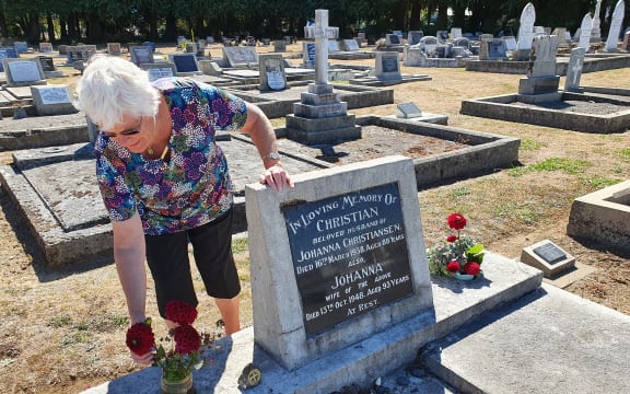 Heather Cheer places red flowers and a symbol of the scandi wheel on one of the graves of Scandinavian settlers at the Norsewood Cemetery