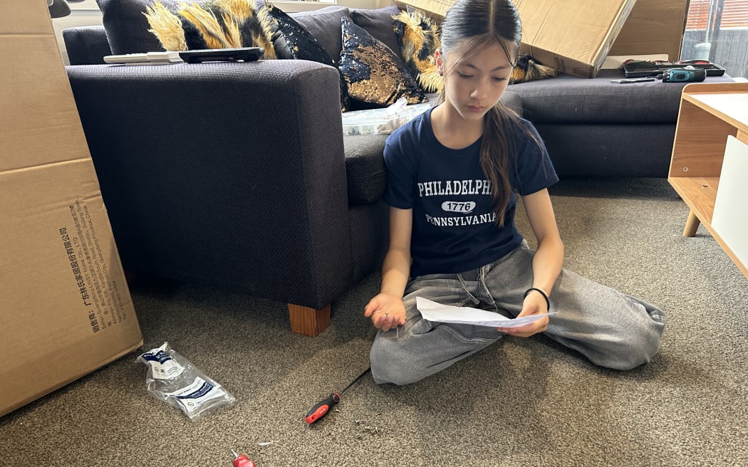 Picture of a young woman sitting on the floor and staring at some instructions.