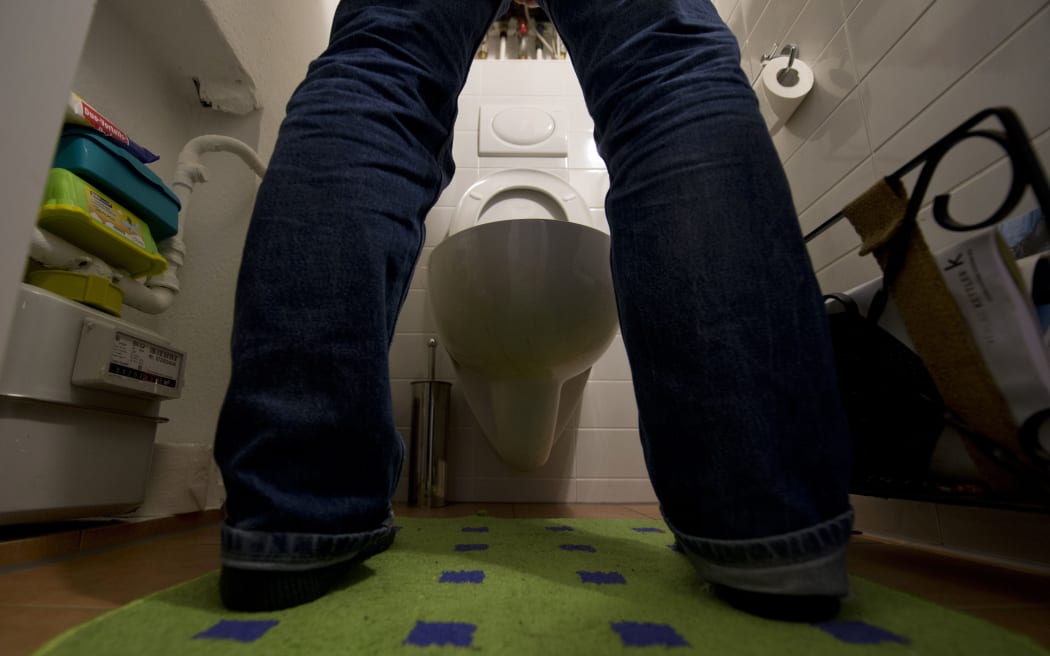 A man stands in front of a western-style toilet bowl in a Berlin flat on 22 January.