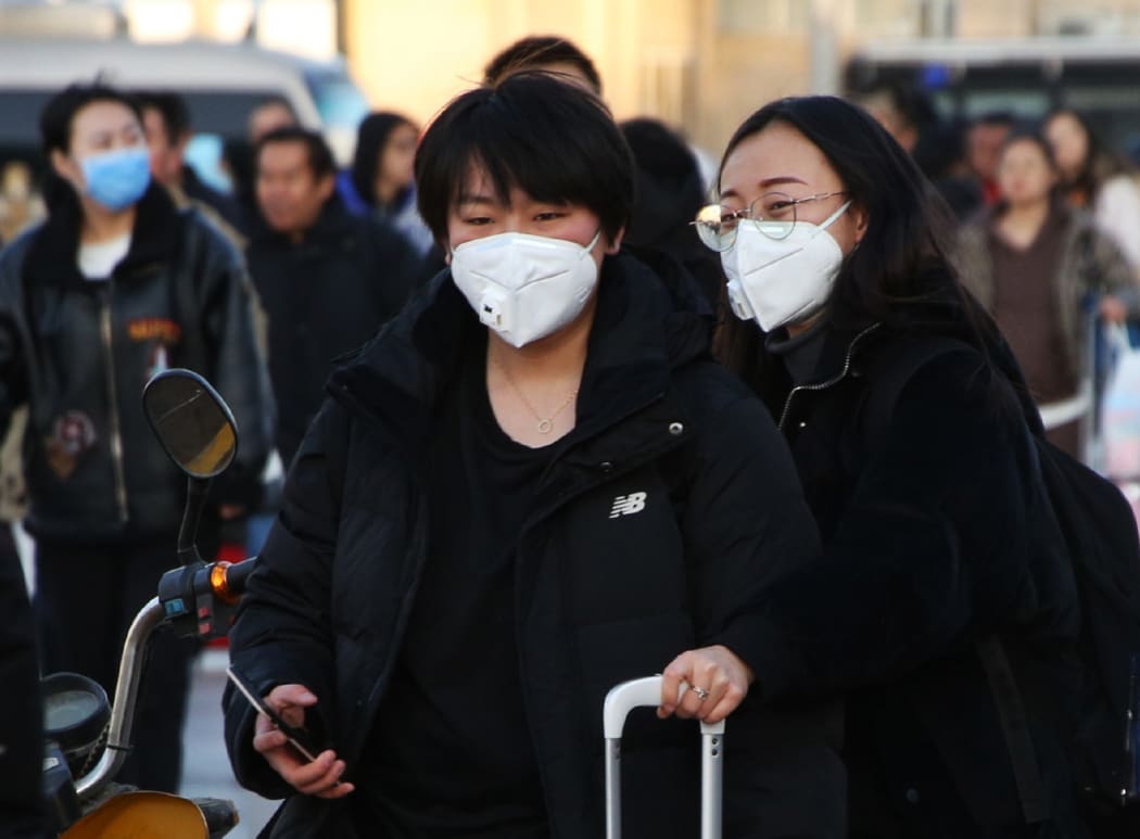 People wearing masks head for Beijing Station in Beijing, China on 20 January, ahead of China's Lunar New Year holiday. Tens of thousands of people travel and visit overseas during the holiday.