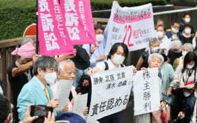 Plaintiffs of Tokyo Electric Power Co. (TEPCO) shareholders holds a banner " Shareholders win the case" at Tokyo District Court in Chiyoda Ward, Tokyo on July 13, 2022. The court ordered four former executives of Tokyo Electric Power Co.(TEPCO) to pay some 13 trillion yen, approximately $97 billion to shareholders in compensation for failing to prevent the 2011 Fukushima nuclear crisis. ( The Yomiuri Shimbun ) (Photo by Miho Takahashi for Pool / Yomiuri / The Yomiuri Shimbun via AFP)