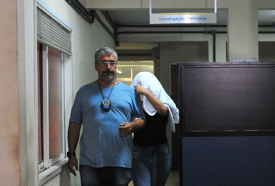 A civil policeman escorts the wife of Greece's ambassador to Brazil Kyriakos Amiridis, Francoise Amiridis, on 30 December in Rio de Janeiro.