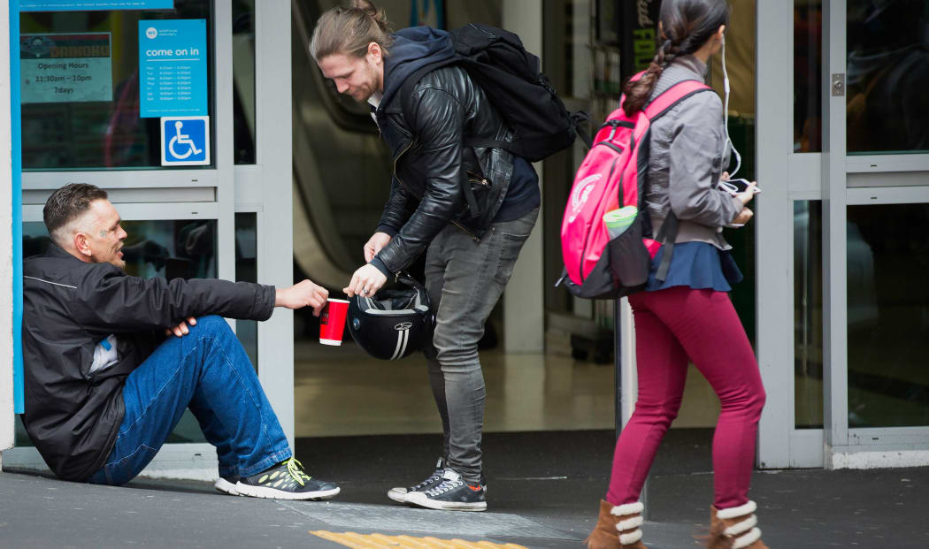 A man gives a beggar change on Auckland's Queen Street.