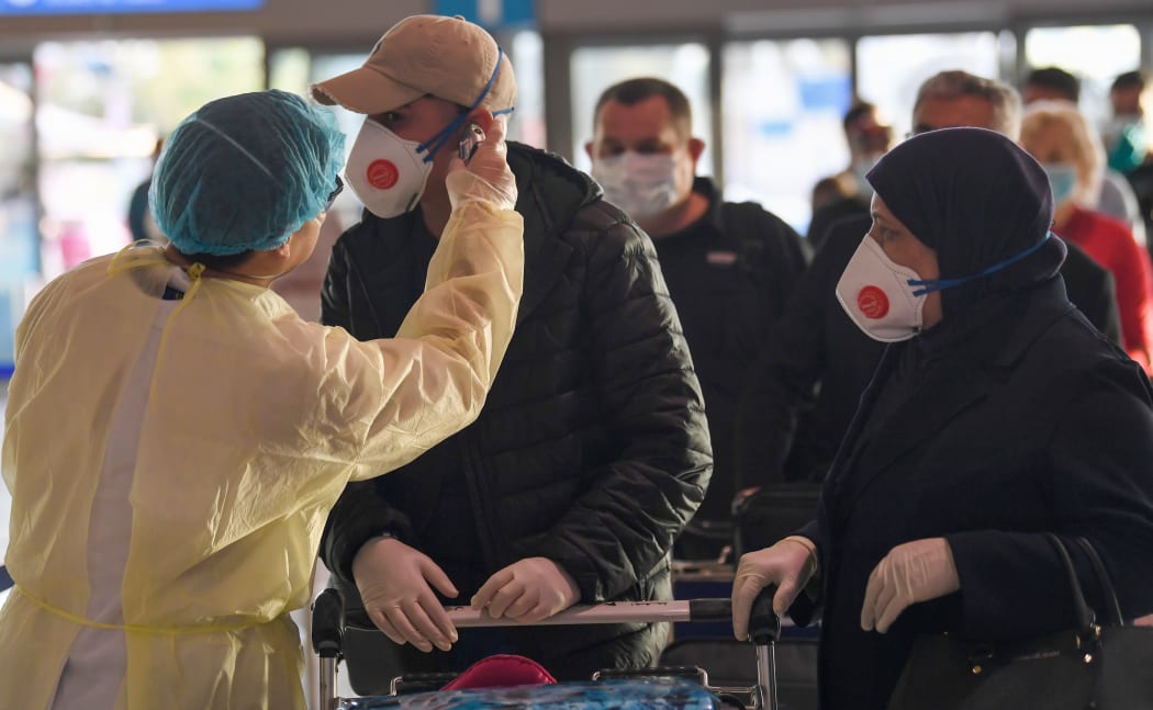 A health worker checks the body temperature of passengers bound for Frankfurt at Dubai International Airport on April 6, 2020, as Emirates Airline resumed a limited number of outbound passenger flights after its Covid-19 coronavirus-enforced stoppage.