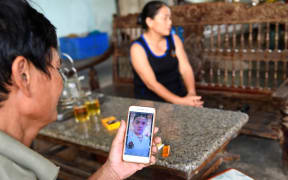 Hoang Lanh, father of 18-year old Hoang Van Tiep who is feared to be among the 39 people found dead in a truck in Britain, looks at his son's photograph on his phone at their house in Dien Thinh commune of Vietnam's Nghe An province on October 28, 2019