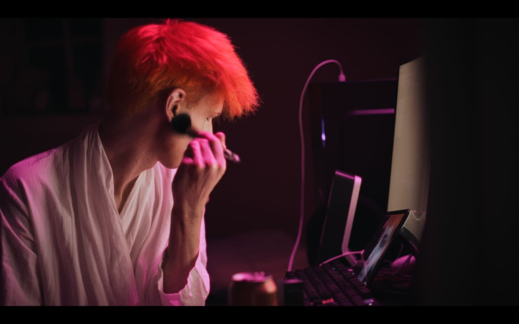 Ari Kerssens applies makeup in front of his computer