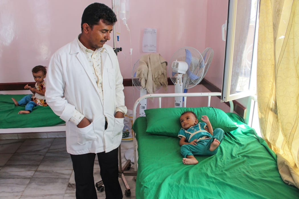 A hospital staffer looks at a Yemeni child suffering from malnutrition lying on a bed at a hospital in the northern district of Abs in the northwestern Hajjah province on September 19, 2018.