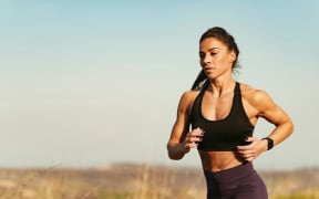 Woman running in sports bra outdoors.