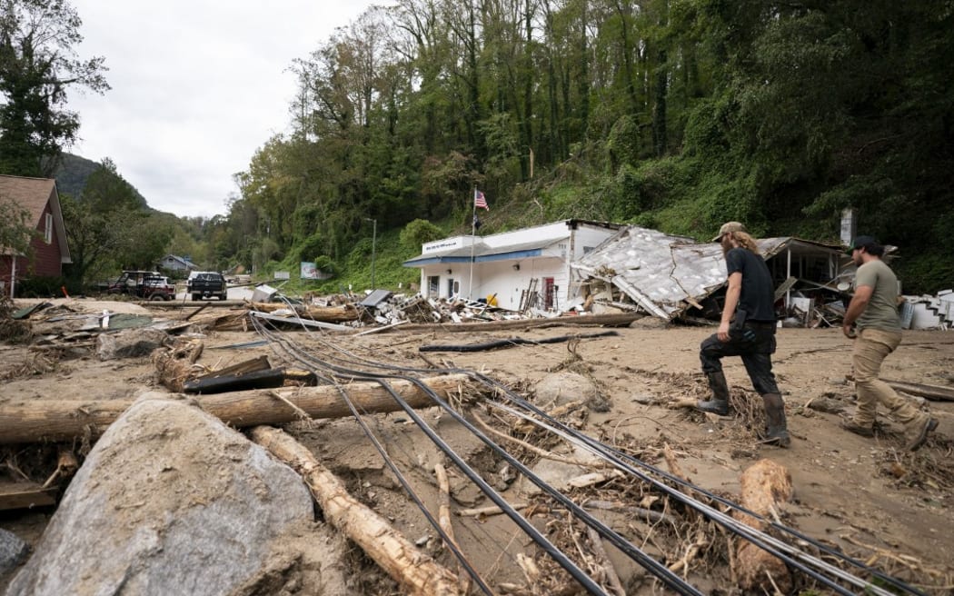 BAT CAVE, NORTH CAROLINA - OCTOBER 1: Men walk along North Carolina Route 9 in the aftermath of Hurricane Helene on October 1, 2024 in Bat Cave, North Carolina. The death toll has topped 140 people across the southeastern U.S. due to the storm, according to published reports, which made landfall as a category 4 storm on Thursday. Millions are without power and the federal government has declared major disasters in areas of North Carolina, Florida, South Carolina, Tennessee, Georgia, Virginia and Alabama, freeing up federal emergency management money and resources for those states, according to the reports.   Sean Rayford/Getty Images/AFP (Photo by Sean Rayford / GETTY IMAGES NORTH AMERICA / Getty Images via AFP)