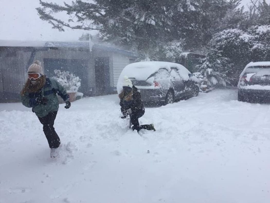 Guests play in the snow outside a lodge near the Tongariro Crossing.