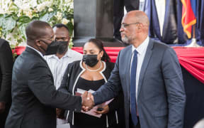 Designated Prime Minister Ariel Henry (R) shakes hands with Minister of Foreign Affairs and Worship Claude Joseph during a ceremony at La Primature in Port-au-Prince, Haiti