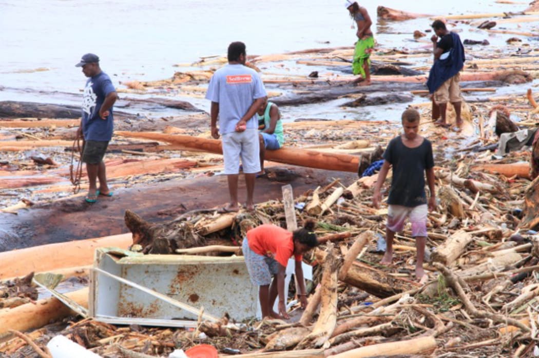 People search the rubble left by flooding in the Solomon Islands.
