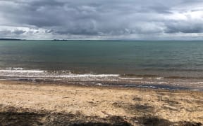 beach with calm sea and dark grey clouds