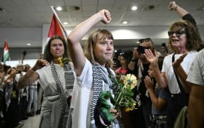Swedish climate campaigner Greta Thunberg raises her fist, upon arrival alongside activists who were sailing aboard vessels from the Gaza-bound aid flotilla before being stopped and detained by Israeli forces, at the arrivals area of Athens International Airport on 6 October, 2025.