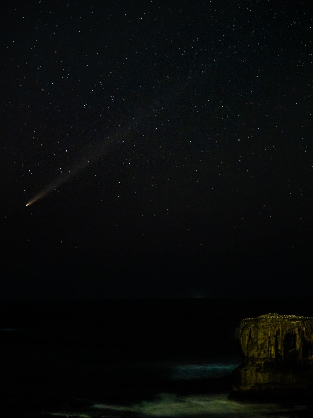 John Tsai captured this image at Muriwai Saturday 19 October when the comet was closer to the horizon and when the gannet colony in view.