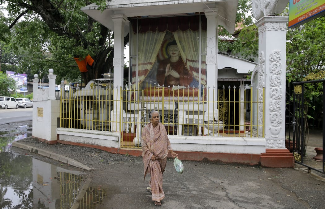 An elderly Sri Lankan Muslim woman walks past a Buddhist shrine in Colombo, Sri Lanka, Thursday, May 2, 2019.