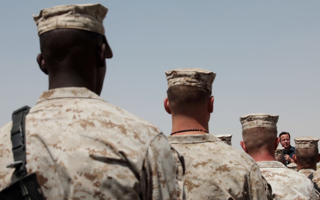 Britain's Prime Minister David Cameron  (R) gives a July 4 address to British and American troops at Camp Leatherneck military base in Helmand Province on July 4, 2011.  Cameron was forced today to scrap a visit to an Afghan town he had held up as an example of improved security after a soldier went missing in the area.  The Taliban claimed that its fighters had kidnapped and killed a British soldier in Helmand, but there was no independent confirmation and the militia is known to routinely exaggerate its claims. AFP PHOTO / POOL / David Bebber (Photo by DAVID BEBBER / POOL / AFP)