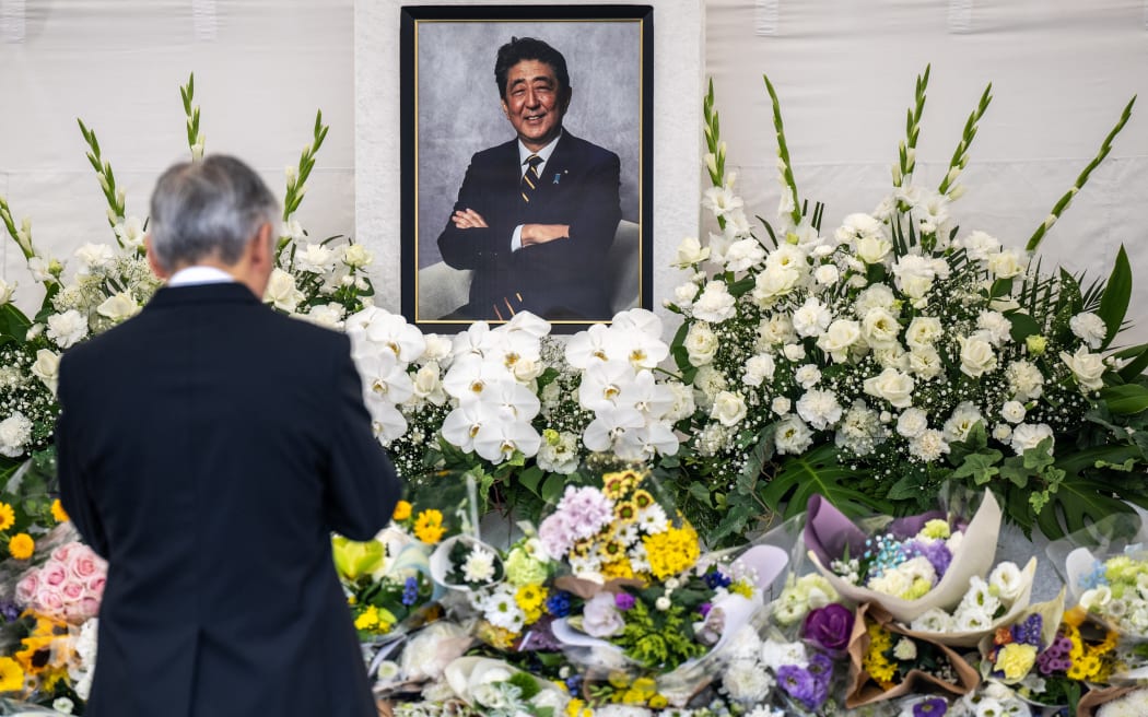 A man pays his respects during a memorial service on the first death anniversary of Japan's former prime minister Shinzo Abe, at Zojoji Temple in Tokyo on July 8, 2023. Abe, the country's longest serving leader, was assassinated in broad daylight while giving a campaign speech in western Japan, targeted by a man allegedly angry over the former leader's links to the Unification Church. (Photo by Philip FONG / AFP)