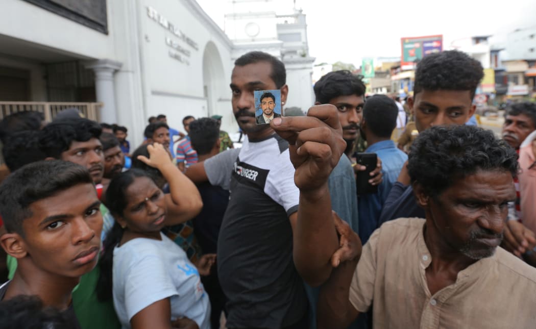 A Sri Lankan catholic devotee holds a blood-stained photograph as people wait to identify dead bodies of their loved ones in front of the St Anthony's Church.