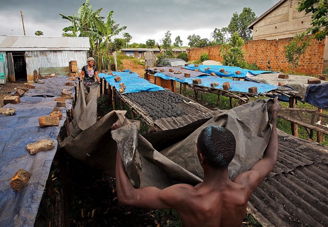 Workers cover biochar to dry in the sun before it is packed and distributed at the Eco Fuel Africa factory  in Lugazi on January 29, 2013.  The process produces a powder which can be used as an organic fertilizer or compressed for use as a bio fuel which burns longer than charcoal.